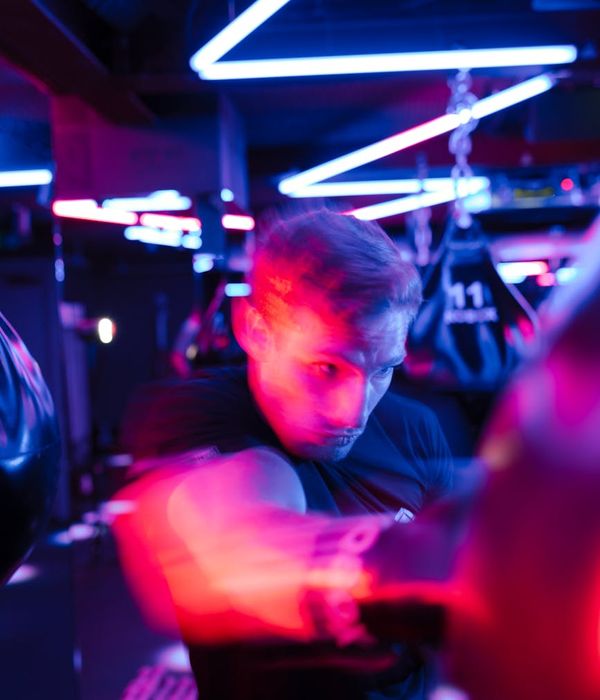 Athletic man performing strength exercises in a neon lit gym environment